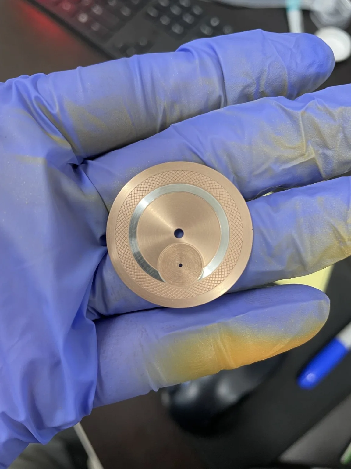 Physical salmon-toned dial on a blue glove, without applied numerals or printed markings